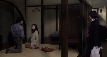Movie still from “Ringu” (1998), directed by Hideo Nakata – A woman sitting on the ground in a room; Wide shot, High angle