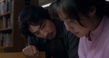 Movie still from “Ringu” (1998), directed by Hideo Nakata – A man and a woman looking at a piece of paper; Close Up shot, High angle