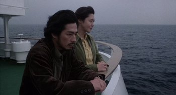Movie still from “Ringu” (1998), directed by Hideo Nakata – A man and a woman sitting on a boat in the water; Medium shot, High angle