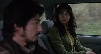 Movie still from “Ringu” (1998), directed by Hideo Nakata – A man and a woman sitting in the back of a car; Close Up shot, Over the shoulder angle
