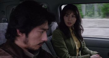 Movie still from “Ringu” (1998), directed by Hideo Nakata – A man and a woman sitting in the back of a car; Close Up shot, Over the shoulder angle