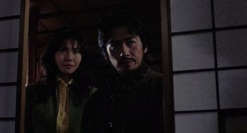 Movie still from “Ringu” (1998), directed by Hideo Nakata – A man and a woman standing next to each other; Medium shot, Low angle