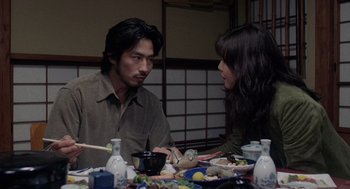 Movie still from “Ringu” (1998), directed by Hideo Nakata – A man and a woman sitting at a dinner table; Medium shot, Over the shoulder angle