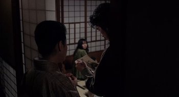 Movie still from “Ringu” (1998), directed by Hideo Nakata – Two people standing in front of each other holding papers; Medium shot, Over the shoulder angle