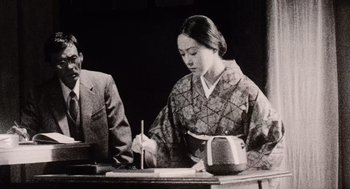 Movie still from “Ringu” (1998), directed by Hideo Nakata – An old photo of a woman sitting at a table; Medium shot, Low angle