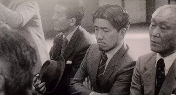 Movie still from “Ringu” (1998), directed by Hideo Nakata – A black and white photo of two men in suits and hats; Close Up shot, High angle