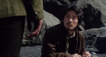 Movie still from “Ringu” (1998), directed by Hideo Nakata – A man sitting on the ground in front of a person; Close Up shot, Over the shoulder angle