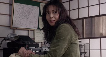 Movie still from “Ringu” (1998), directed by Hideo Nakata – A woman holding a remote control in a room; Close Up shot, High angle