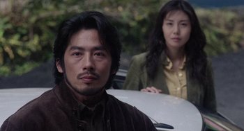 Movie still from “Ringu” (1998), directed by Hideo Nakata – A man and a woman sitting next to each other; Close Up shot, Over the shoulder angle