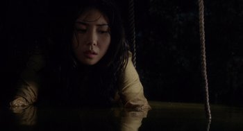 Movie still from “Ringu” (1998), directed by Hideo Nakata – A young woman sitting on a rope in the dark; Close Up shot, Overhead angle