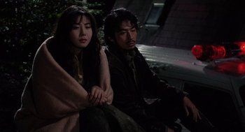 Movie still from “Ringu” (1998), directed by Hideo Nakata – A man and a woman sitting next to each other on a bench; Medium shot, High angle