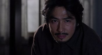 Movie still from “Ringu” (1998), directed by Hideo Nakata – A person wearing a brown shirt; Close Up shot, Low angle