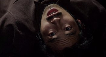 Movie still from “Ringu” (1998), directed by Hideo Nakata – A man with his head upside down in a dark room; Extreme Close Up shot, Overhead angle