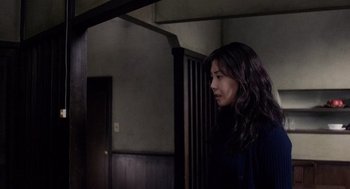 Movie still from “Ringu” (1998), directed by Hideo Nakata – A woman standing next to a wooden wall; Medium shot, Over the shoulder angle