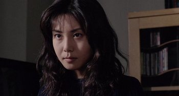 Movie still from “Ringu” (1998), directed by Hideo Nakata – A woman with long black hair is looking at the camera; Close Up shot, Over the shoulder angle