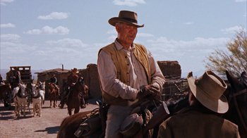 Movie still from “Rio Bravo” (1959), directed by Howard Hawks – An older man in a cowboy hat is riding a horse; Medium shot, Over the shoulder angle