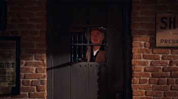 Movie still from “Rio Bravo” (1959), directed by Howard Hawks – An old man in a cowboy hat looking out of a jail cell; Wide shot, Low angle