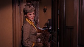 Movie still from “Rio Bravo” (1959), directed by Howard Hawks – A woman wearing a hat and holding a bouquet of feathers; Medium shot, Low angle