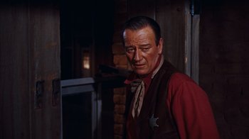 Movie still from “Rio Bravo” (1959), directed by Howard Hawks – A man in a red vest and a star on his shirt; Medium shot, Over the shoulder angle
