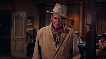 Movie still from “Rio Bravo” (1959), directed by Howard Hawks – A man wearing a cowboy hat in a room; Medium shot, Low angle