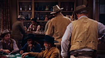 Movie still from “Rio Bravo” (1959), directed by Howard Hawks – A group of men sitting at a table in a room; Wide shot, Over the shoulder angle