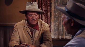 Movie still from “Rio Bravo” (1959), directed by Howard Hawks – A man wearing a hat sitting next to another man; Medium shot, Over the shoulder angle