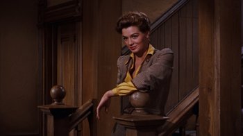 Movie still from “Rio Bravo” (1959), directed by Howard Hawks – A woman leaning on a railing on a staircase; Medium shot, Low angle