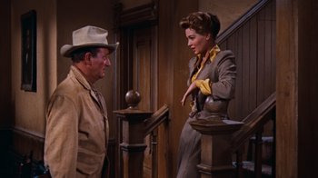 Movie still from “Rio Bravo” (1959), directed by Howard Hawks – A man and a woman standing next to each other on stairs; Medium shot, Low angle