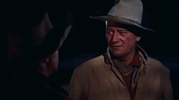 Movie still from “Rio Bravo” (1959), directed by Howard Hawks – A man wearing a cowboy hat and a jacket; Medium shot, Over the shoulder angle