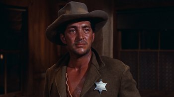 Movie still from “Rio Bravo” (1959), directed by Howard Hawks – A man wearing a sheriff's badge and a brown jacket; Close Up shot, Low angle