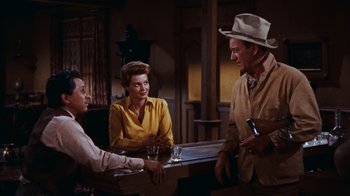 Movie still from “Rio Bravo” (1959), directed by Howard Hawks – A group of people sitting at a table in a room; Medium shot, Over the shoulder angle