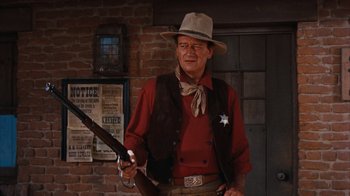Movie still from “Rio Bravo” (1959), directed by Howard Hawks – A man in a cowboy hat holding a gun; Medium shot, Low angle