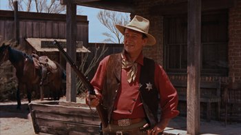 Movie still from “Rio Bravo” (1959), directed by Howard Hawks – A man holding a gun and wearing a cowboy hat; Medium shot, Low angle