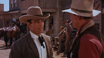 Movie still from “Rio Bravo” (1959), directed by Howard Hawks – A man in a cowboy hat talking to another man in a cowboy hat; Medium shot, Over the shoulder angle