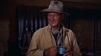 Movie still from “Rio Bravo” (1959), directed by Howard Hawks – A man wearing a hat and holding a cup in his hand; Medium shot, Over the shoulder angle