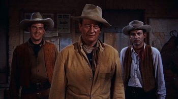 Movie still from “Rio Bravo” (1959), directed by Howard Hawks – A man wearing a cowboy hat standing next to two other men; Medium shot, Low angle