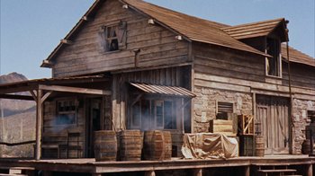 Movie still from “Rio Bravo” (1959), directed by Howard Hawks – An old wooden building with barrels on the front of the building; Extreme Wide shot, Low angle