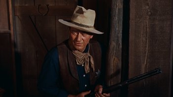 Movie still from “Rio Bravo” (1959), directed by Howard Hawks – A man with a hat holding a gun in his hand; Medium shot, Low angle