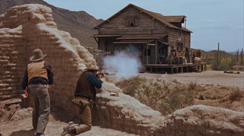 Movie still from “Rio Bravo” (1959), directed by Howard Hawks – A man is shooting a gun in the desert; Wide shot, Low angle