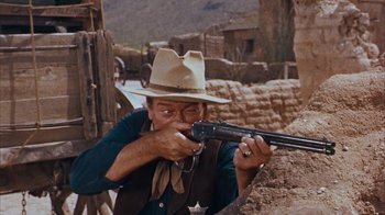 Movie still from “Rio Bravo” (1959), directed by Howard Hawks – A man with a hat and a gun in his hands; Medium shot, Low angle