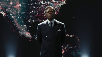 Movie still from “RoboCop” (2014), directed by José Padilha – A man wearing a suit and tie standing in front of a map; Medium shot, Low angle