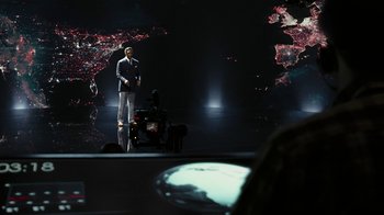 Movie still from “RoboCop” (2014), directed by José Padilha – A man standing on a stage in front of a camera; Wide shot, High angle