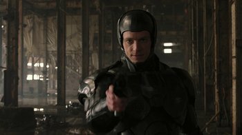 Movie still from “RoboCop” (2014), directed by José Padilha – A man wearing a helmet and holding a gun in his hand; Close Up shot, Over the shoulder angle