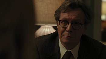 Movie still from “RoboCop” (2014), directed by José Padilha – An older man wearing glasses and a suit and tie; Close Up shot, Over the shoulder angle