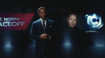 Movie still from “RoboCop” (2014), directed by José Padilha – A man standing in front of an image of a man; Medium shot, Low angle