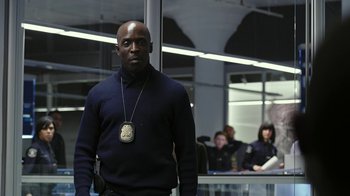 Movie still from “RoboCop” (2014), directed by José Padilha – A man wearing a police badge stands in front of a group of people; Medium shot, Low angle