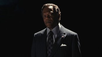 Movie still from “RoboCop” (2014), directed by José Padilha – A man wearing a suit and tie standing in the dark; Close Up shot, Low angle