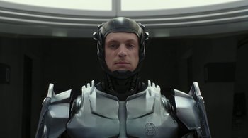 Movie still from “RoboCop” (2014), directed by José Padilha – A man wearing a metal suit and a helmet; Medium shot, Low angle
