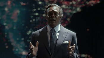 Movie still from “RoboCop” (2014), directed by José Padilha – A man in a suit and tie is talking; Close Up shot, Over the shoulder angle