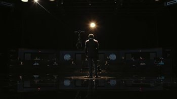 Movie still from “RoboCop” (2014), directed by José Padilha – A man standing in front of a camera in a dark room; Wide shot, Low angle
